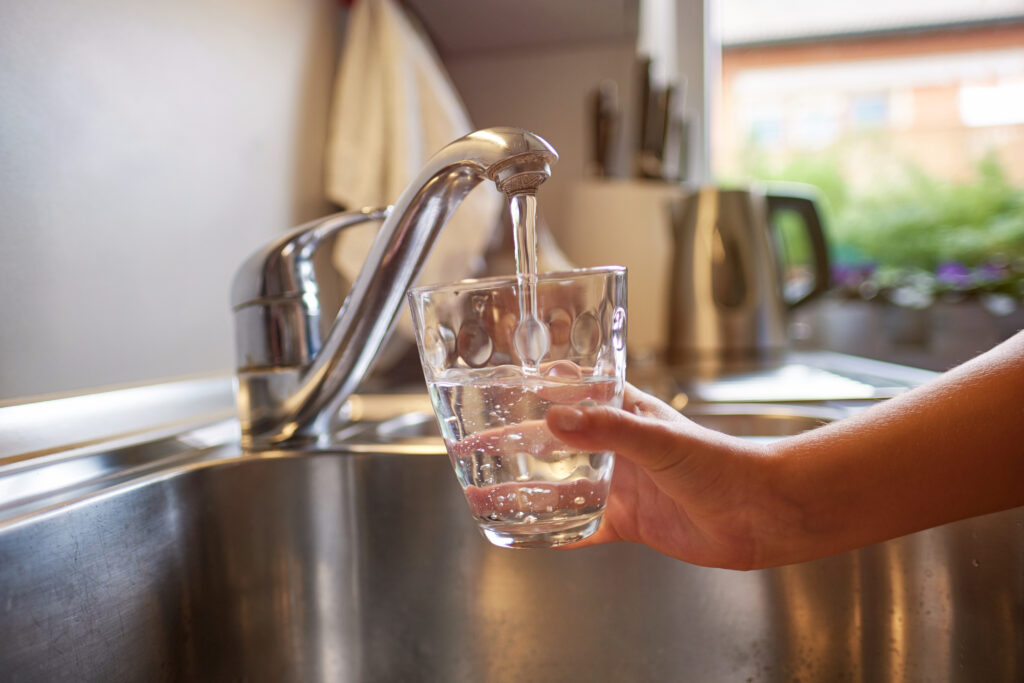 Close up of children hands, pouring glass of fresh water from ta