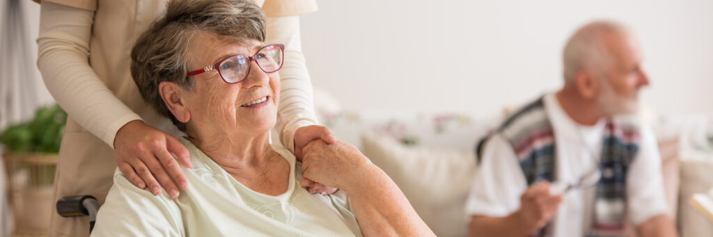 Panoramic view of elderly lady on wheelchair holding hands with