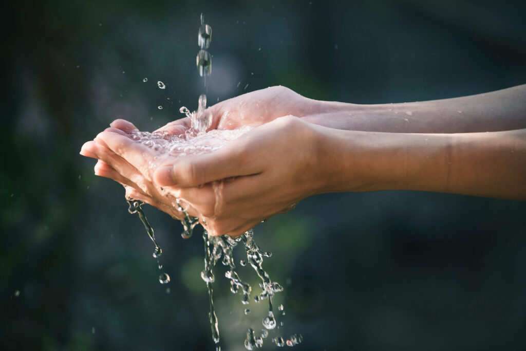 closeup water flow to hand of women for nature concept on the ga